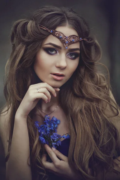 Retrato de uma menina duende com cabelos longos e olhos azuis, usa uma tiara com um buquê de flores da primavera na floresta. Menina Princesa sonhos . — Fotografia de Stock