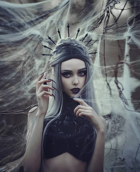 Όμορφη σέξι κορίτσι Gothic με ωχρό δέρμα και μακριά λευκά μαλλιά σαν μαύρη χήρα αράχνη στον ιστό της αράχνης. Σκοτάδι πριγκίπισσα με βαμπίρ μακριά νύχια του στέμματος. Γυναίκα αράχνη ύφανση δίχτυ. Βλέμμα Gothic. — Φωτογραφία Αρχείου
