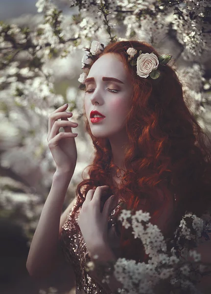 Retrato de una hermosa mujer sensual joven con el pelo rizado rojo muy largo en flores de primavera. Colores de primavera  . —  Fotos de Stock