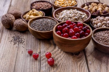 Farklı süper yiyecekler, tohumlar, fındıklar, tahıllar, kızılcıklar, yulaf ezmesi. Vejetaryen sağlıklı beslenme konsepti.