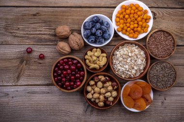 Farklı süper yiyecekler, tohumlar, fındıklar, tahıllar, kızılcıklar, kurutulmuş kayısılar, deniz dikenleri, yabanmersinleri, yulaf ezmesi. Vejetaryen sağlıklı beslenme konsepti. Üst görünüm