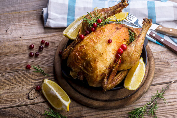 Roast chicken on cutting board in wooden table