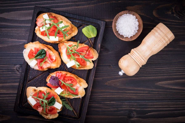 Bruschetta Met Tomaten Mozzarella Kaas Kruiden Een Snijplank Een Donkere — Stockfoto