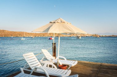 Gün batımında kumsalda güneşlik ve şemsiyeler, Ege denizi, Türkiye