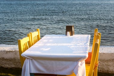 Güzel Ege Denizi yakınlarındaki Bodrum kasabasında masalar. Deniz kenarındaki sahil kafe, Türkiye. Gün batımı.