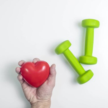 Kalbi spor aletleriyle tutun, halterlerle, beyaz arka planda. Yukarıdan yukarıdan bir görüntü. Sağlık ve egzersiz kavramı