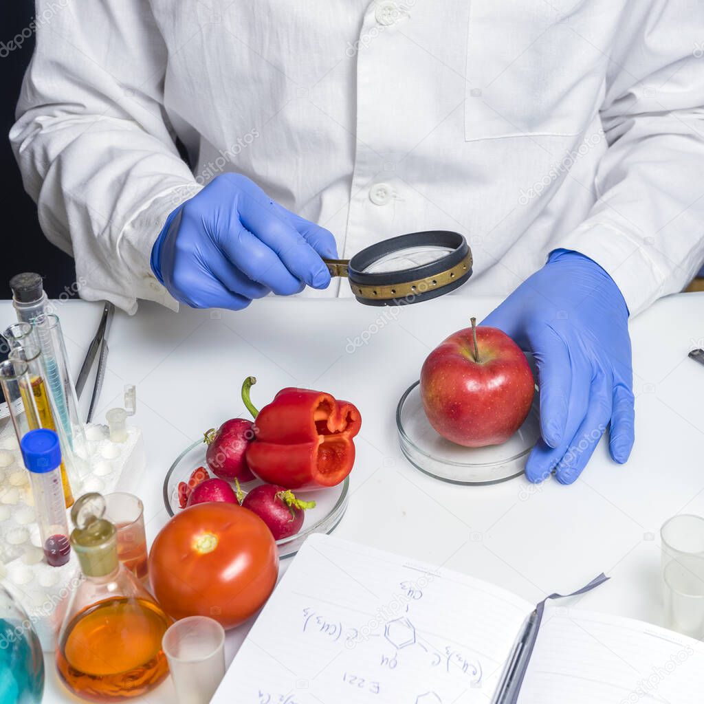 Food safety expert checking red apple in the laboratory. Close up.