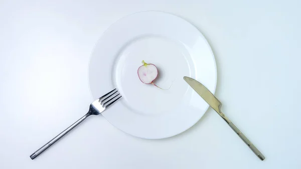Kés és villa, retek egy tányéron, fehér háttérrel. Diétás fogalom. — Stock Fotó