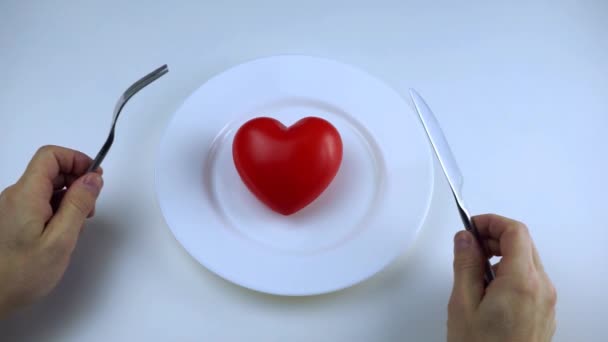 男人的手拿着一把刀叉 心脏在盘子里 白色背景 饮食概念 — 图库视频影像