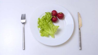 Diet concept. fresh vegetables on a white plate with fork and knife.