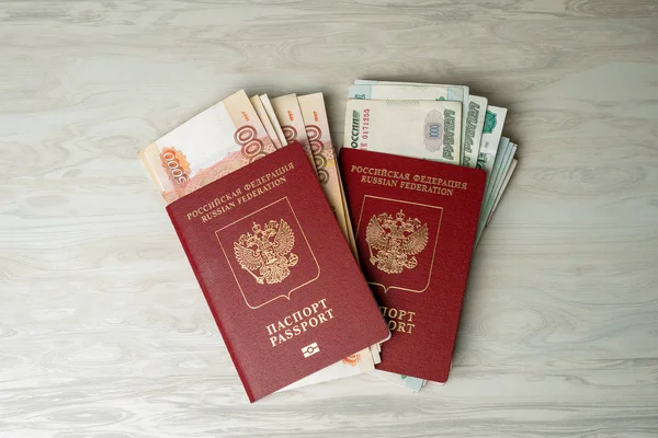 Yurt dışında alışveriş, seyahat ve eğlence için parası olan Rus pasaportu. Masa lambası arka planında para yatıyor.