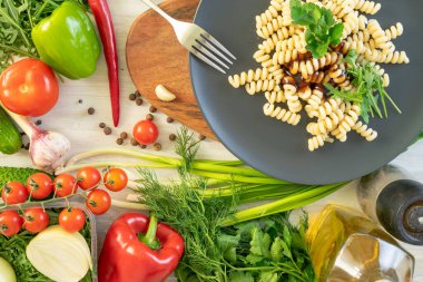 üzerinde siyah servis tabağı, patlıcan, biber ve domates penne makarna. fesleğen ile süslenmiş.
