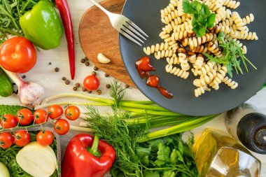 üzerinde siyah servis tabağı, patlıcan, biber ve domates penne makarna. fesleğen ile süslenmiş.