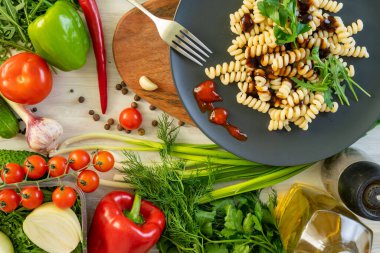 üzerinde siyah servis tabağı, patlıcan, biber ve domates penne makarna. fesleğen ile süslenmiş.