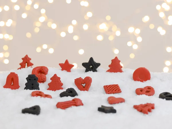 Красное Черное Рождественское Печенье Белом Снегу Сияющими Огнями Заднем Плане — стоковое фото