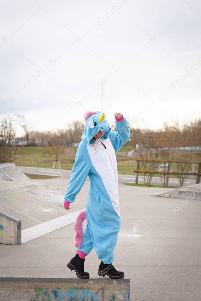 beautiful young woman wearing turquoise unicorn onesie in urban environment