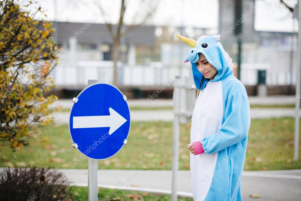 beautiful young woman wearing turquoise unicorn onesie in urban environment