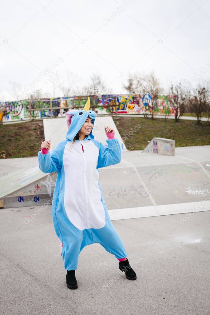 beautiful young woman wearing turquoise unicorn onesie in urban environment