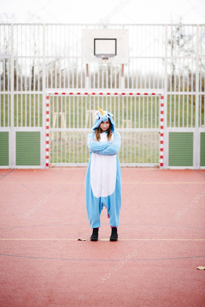 beautiful young woman wearing turquoise unicorn onesie in urban environment