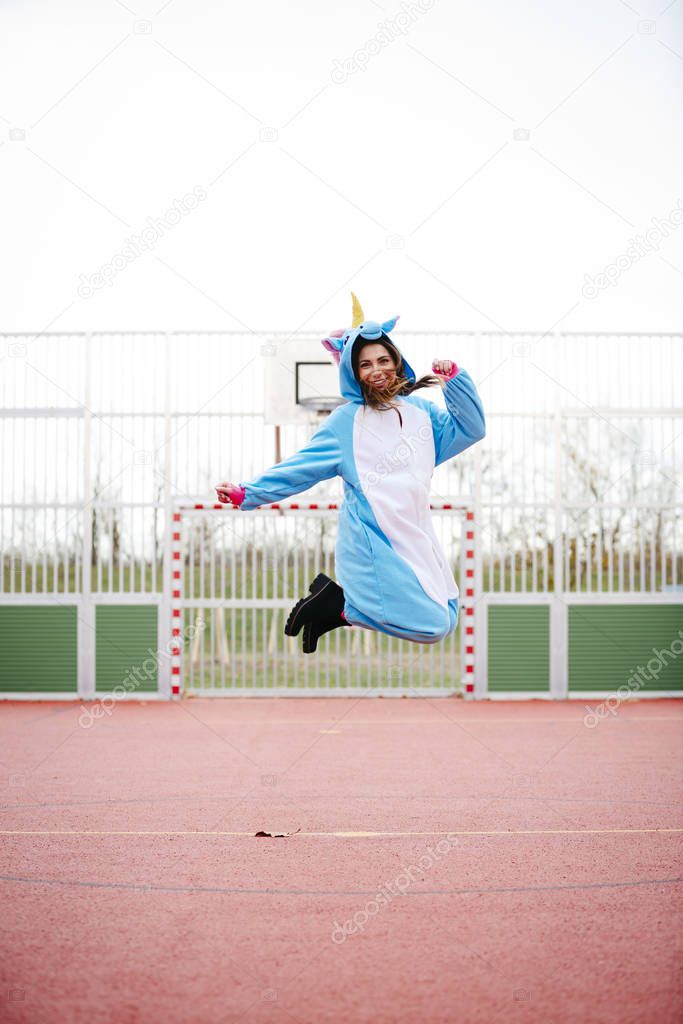 beautiful young woman wearing turquoise unicorn onesie in urban environment