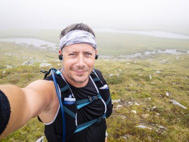 Avusturya 'daki Carinthian dağlarında spor giyimli koşan adamın selfie' si. 
