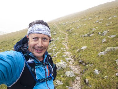 Avusturya 'daki Carinthian dağlarında spor giyimli koşan adamın selfie' si. 