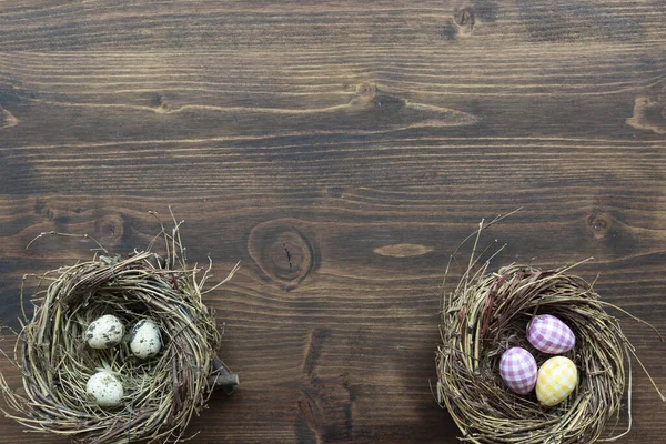 bird nests with colorful painted eggs on wooden background, easter concept