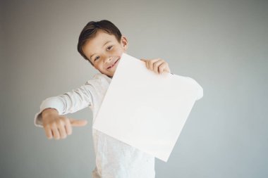 Gri arka planda beyaz çarşaf tutan havalı genç çocuk. 