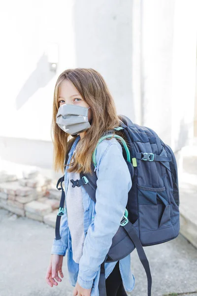 pretty girl with nose mouth mask goes to school after the corona quarantine