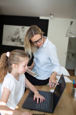 Corona krizi sırasında evde kızıyla birlikte çalışan bir kadın.