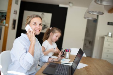 Corona krizi sırasında evde kızıyla birlikte çalışan bir kadın.