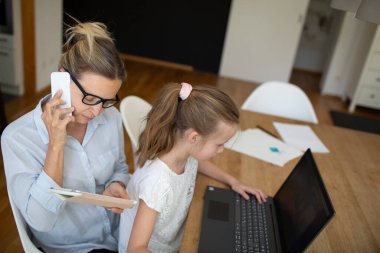 Corona krizi sırasında evde kızıyla birlikte çalışan bir kadın.