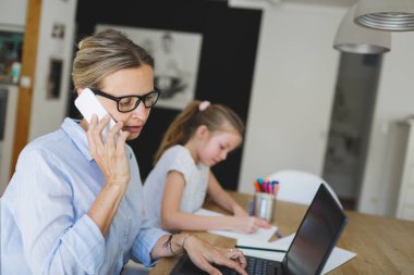 Corona krizi sırasında evde kızıyla birlikte çalışan bir kadın.