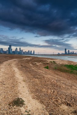 Sıcak, güneşli bir günde güzel, beyaz, kumlu bir plajın üzerinde modern, metropoliten bir şehir kulesinin uzun gökdelenleri..