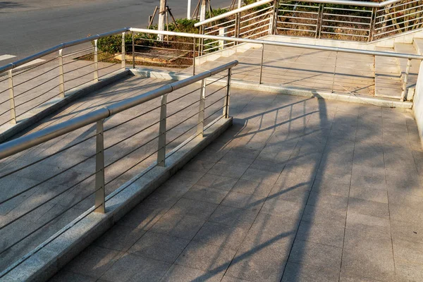 A wheelchair ramp, an inclined plane installed in addition to or instead of stairs, Slope walkway for disabled people, people pushing strollers, carts with stainless bars to prevent falling