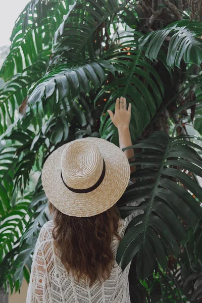 Retrato de una hermosa niña con un sombrero en las hojas de una palmera — Foto de Stock