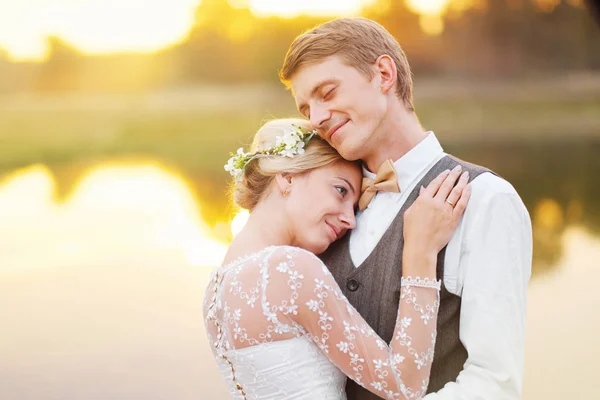 Casal em traje de casamento contra o pano de fundo do campo ao pôr do sol, a noiva eo noivo — Fotografia de Stock