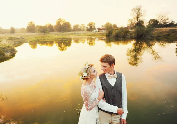 Casal em traje de casamento contra o pano de fundo do campo ao pôr do sol, a noiva eo noivo — Fotografia de Stock