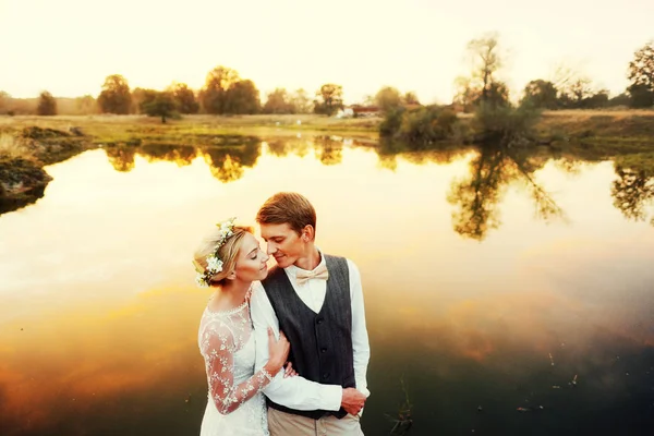 Casal em traje de casamento contra o pano de fundo do campo ao pôr do sol, a noiva eo noivo . — Fotografia de Stock