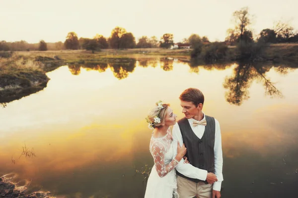 Par i bröllop klädsel mot bakgrund av fältet på solnedgången, bruden och brudgummen. — Stockfoto