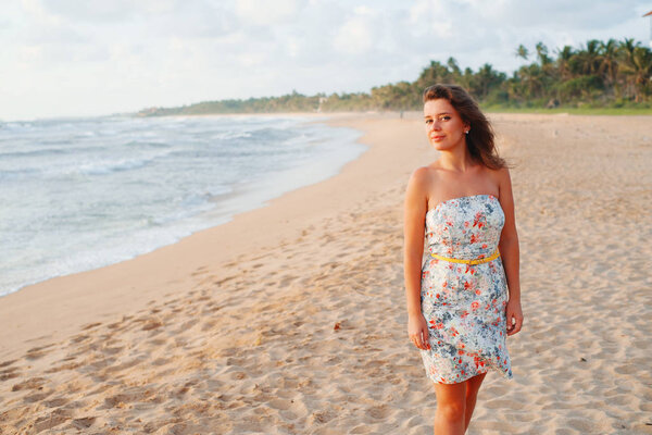 Girl in a dress on the beach near the ocean