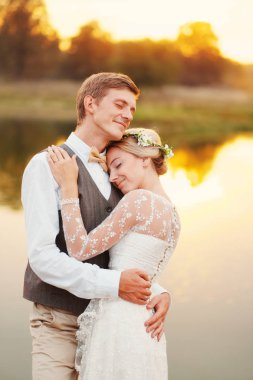 Gelin ve damat ile kapalı gözler göle fonunda sarılma