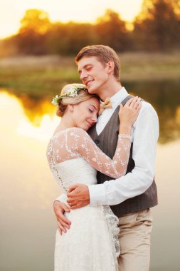 Gelin ve damat ile kapalı gözler göle fonunda sarılma