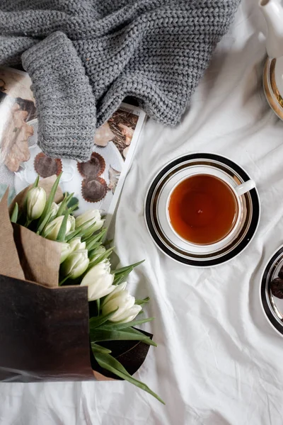 A cozy photo. Top view of a cup of tea and a bouquet of white tulips — Stock Photo, Image