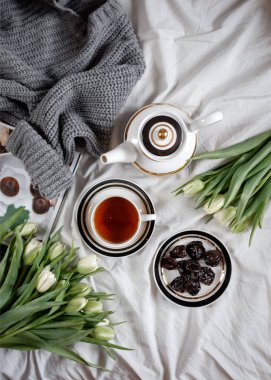 Sabah ile rahat bir yatakta çay ve beyaz laleler