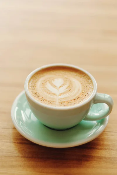 En kopp kaffe i en vacker kopp på ett woodern bord på caféet. — Stockfoto