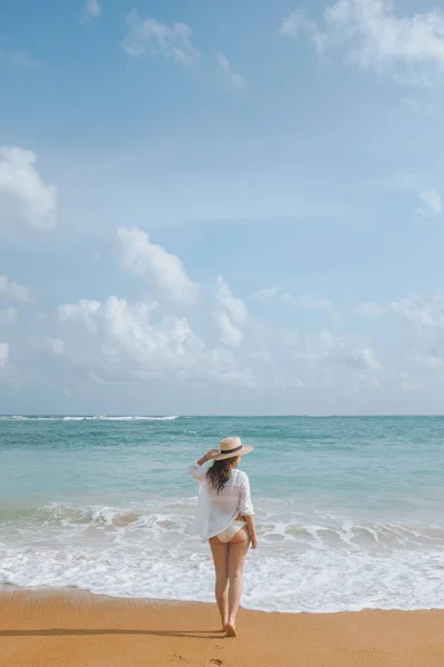 Meisje in een stro hoed wandelen langs het strand — Stockfoto