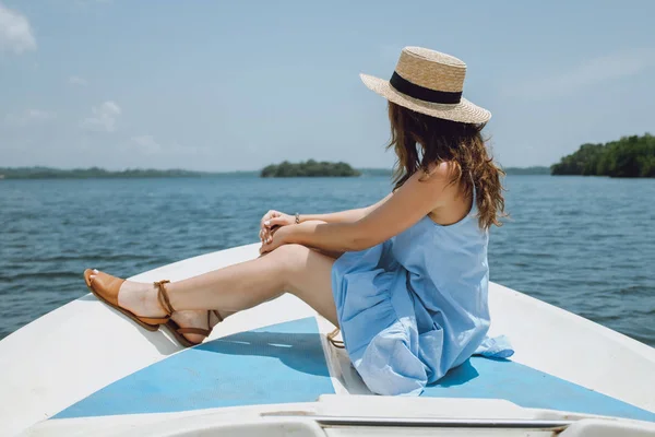 Jonge vrouw in een hoed zit aan de voorzijde van de zeilboot en bewondert de weergave — Stockfoto