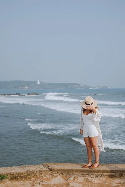 Meisje in een hoed wuiven in de wind lichte witte kleren rondlopen van de Oceaan — Stockfoto
