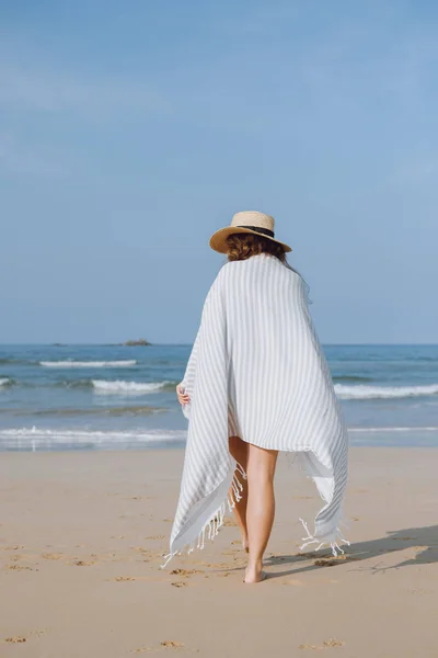 Meisje in een hoed wandelen langs het strand — Stockfoto
